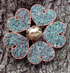 Bronze cast face smiling from the middle of this multimedia copper heart flower sculpture created by Daune Price-Hannah with Work Of Art Studios.
